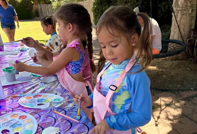 A wooden toy car being hand-painted in bright colors